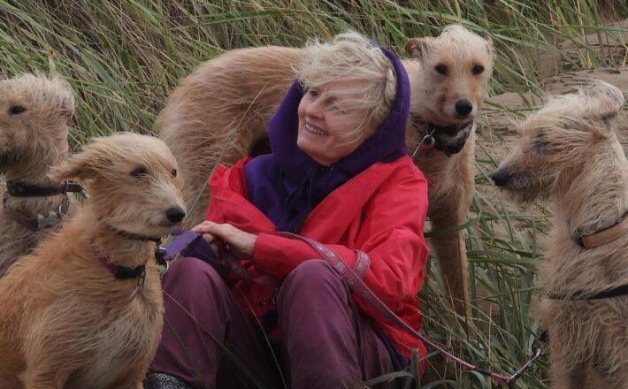 woman with four dogs on a windswept beach