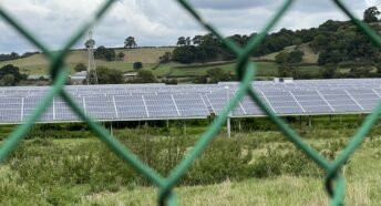 solar panels seen through a chainlink fence